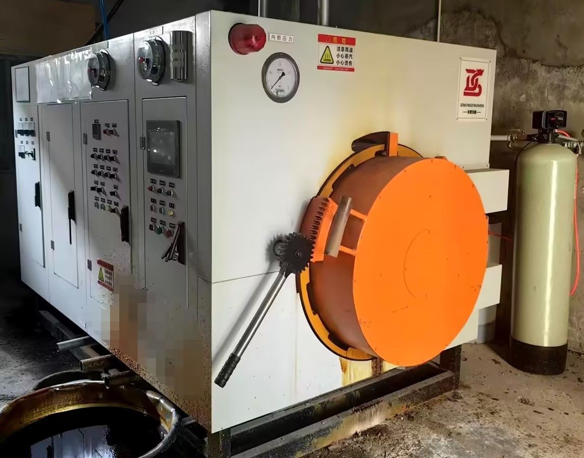 Large industrial machine with an orange door and multiple control panels, installed in a workshop environment.